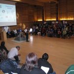 Man giving a presentation in a great hall.