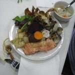 salmon, vegetables, soup and other traditional foods on a plate